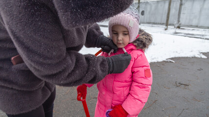 Grandmother with little girl granddaughter on snowy weather outdoors.