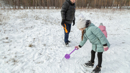 Little girls with her grandfather walk in a snowy forest, have fun together