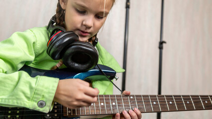 Little girl playing electric guitar on at home