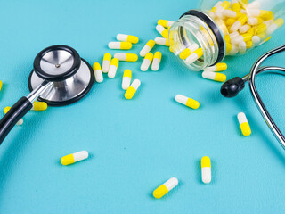 Pills next to stethoscope on light green background. Medicine concept.