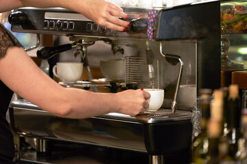 Baristo at work. Women's hands brew aromatic coffee in the coffee machine.