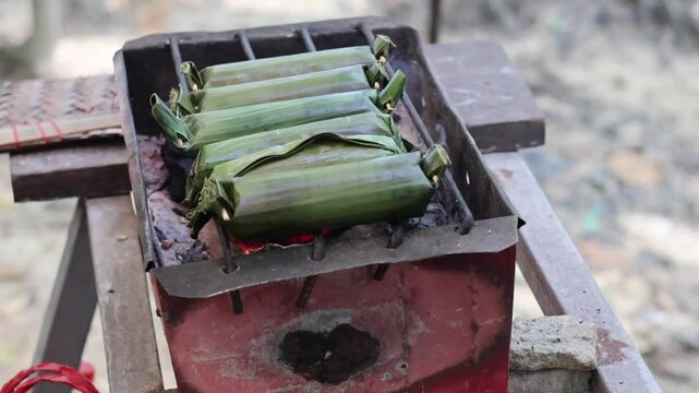 Process Baking Gogos on the grill, Gogos is a typical food from the Indonesia made from white sticky rice mixed with coconut milk and filled with fish, then wrapped in banana leaves and grilled.