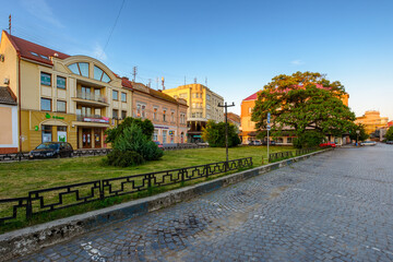 uzhhorod, ukraine - 04 jun 2017: koriatovycha square in morning light. cobblestone street of the old town. capital of transcarpathia. cloudless peaceful blue sky in summer