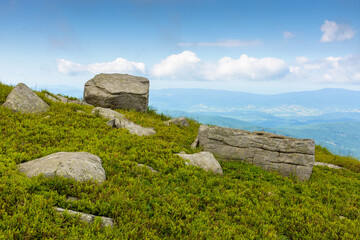 boulder on a hill under blue sky with clouds in summer. huge sandstone among the grass. view in to the distant valley and vihorlat ridge on the horizon