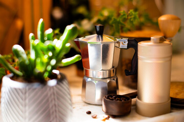 Ingredients for making coffee. Moka coffee maker, coffee grinder with coffee beans are on the table of a cozy kitchen.