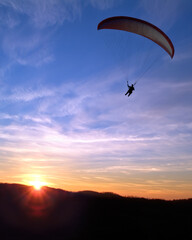 Paraglider in mid air against a dusk sky