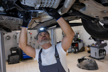 Mechanic with headlamp under vehicle