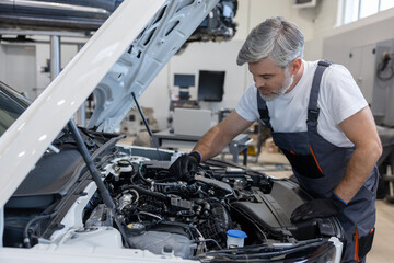 Mechanic checking engine oil in workshop