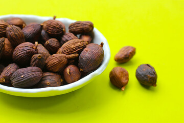 Black Cardamom on green background.