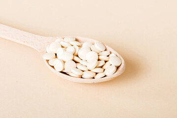 Heap of white pills on colored background. Tablets scattered on a table. Pile of red soft gelatin...