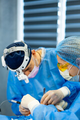Surgeons performing a delicate operation. Two surgeons in protective gear focus intently as they...