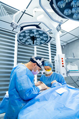 Surgeons at work in hospital. Two surgeons in scrubs are focused on a surgical procedure in a...