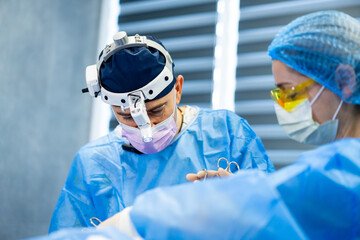 Surgeons at work in OR. Two skilled surgeons focus on a surgical procedure, wearing masks and...