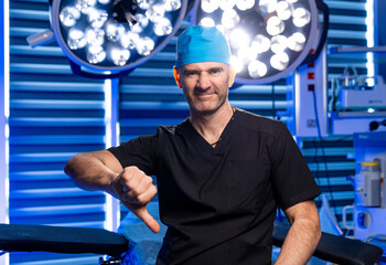 Surgeon shows disapproval in OR. A surgeon in scrubs and a cap shows a thumbs down gesture in a...