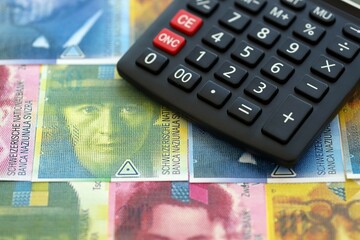 Swiss franc banknotes and calculator. The francs money bills and calc lies on table