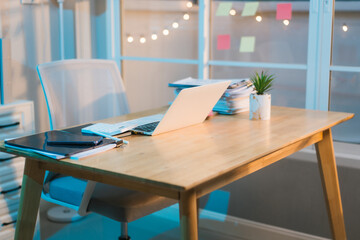 A well-lit, modern office space features a wooden desk with a laptop, tablet, and plant, suggesting a calm and productive work environment. Colorful notes add a touch of personality.