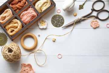 Handmade crafts workspace with yarn threads scissors and crochet hooks on a rustic white table...