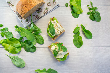 Sandwich with herring paste and greens on a light wooden table