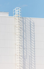 A white ladder on a building with a blue sky in the background