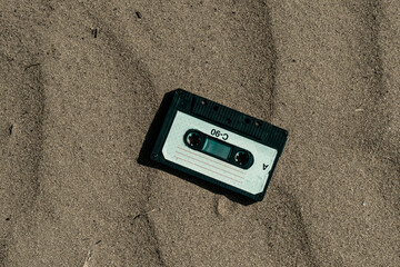 Vintage audio cassette tape in the sand. Retro concept. Toned.