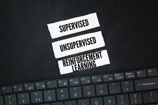 Laptop keyboard and paper with words The three machine learning types are supervised, unsupervised, and reinforcement learning. What are the three types of AI learning?