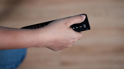 hand holding hand pressing the power button on the TV remotea mobile phone