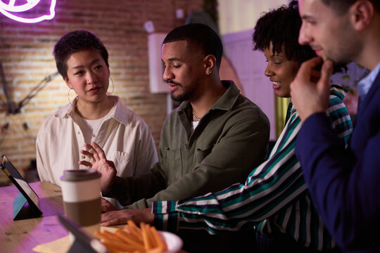 Diverse business team collaborating on a project using tablet in modern office space