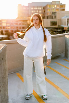 Stylish gen z teen posing on parking garage rooftop at sunset