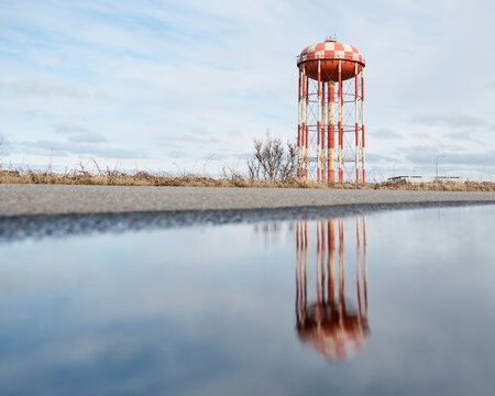 Water tower reflecting in puddle by roadside