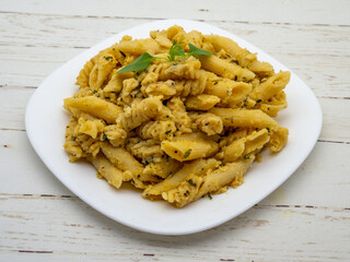 mix of penne quatro formaggi garnished with basil leaf on top on white plate