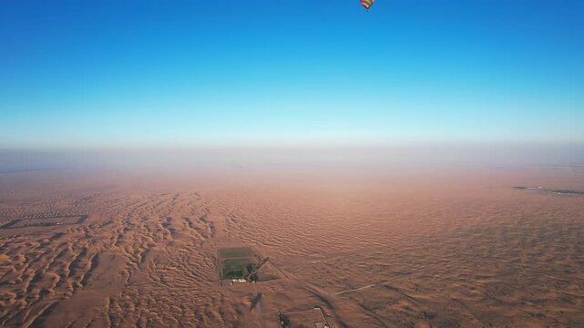 Drone flies around balloons with tourists over the sand dunes of the desert in Dubai