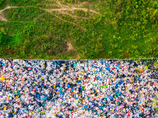 Aerial top view of concept contrast between clean green meadow and plastic landfill. 
