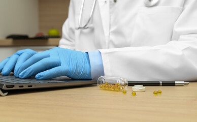 The doctor enters the patient's data into the computer, a vial of medicine lies on the floor