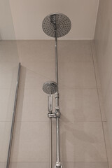 Upward view of chrome shower fixture with large round head and smaller handheld shower head