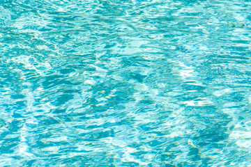 light blue water with ripples on the surface. Defocus blurred transparent clear water surface texture. Water waves with shining patter texture background