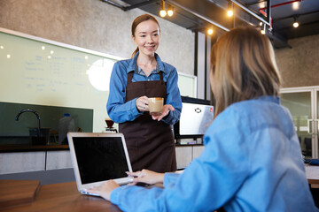 Obraz premium young barista meeting and talking with customer in the cafe