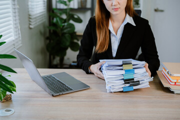 Cropped shot of busy businesswoman sorting through cluttered documents and folders. Completed and...