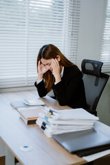 Unhappy female working in the office sitting on office desk while using laptop computer, front...