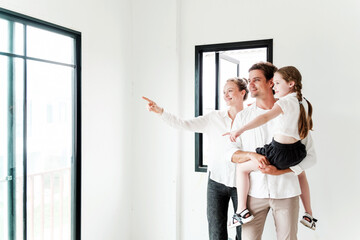 Happy family exploring their new house, pointing out features with excitement. Ideal for real...