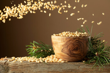 Flying peeled pine nuts on a brown background.