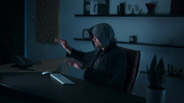 Hooded man sliding an invisible manipulatable hologram in his room - Powered by Adobe