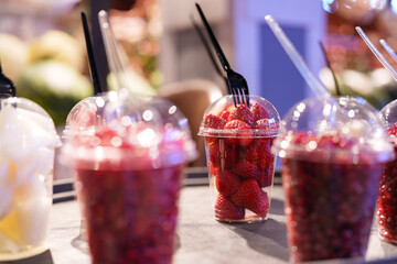 Fresh strawberries arranged in cups for sale at a market during daytime