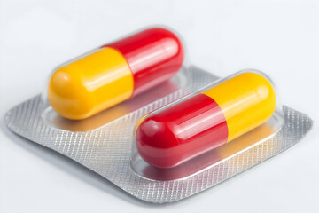 Two red and yellow capsules in a blister pack on a white background.