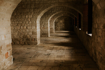 A photograph capturing a stone tunnel with a series of arches inside a fortress in Dubrovnik