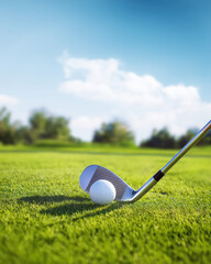 close-up of a golf club poised to hit a golf ball on a pristine green field under a clear blue sky, evoking focus, precision, and the beauty of the game