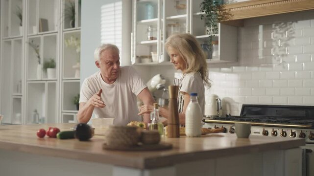 Calm sunday morning in home kitchen, old man and woman cooking breakfast. Happiness and joy of senior spouses, careful wife making snack-box for mature man, low-calories vegetables diet in old age
