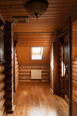 Interior of a cozy wooden house with log walls, wooden floor, and a skylight window letting in natural light.