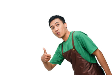 Smiling young Asian man in green shirt and brown apron giving a thumbs-up with a friendly and...