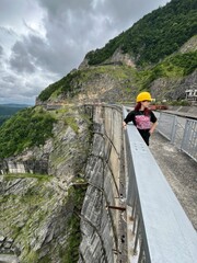 Exploring a high dam site with stunning views of the rugged mountains and lush greenery on a cloudy day in nature