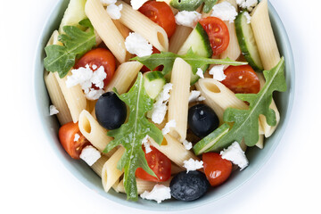 Mediterranean Pasta Salad in bowl with Fresh Vegetables and Herbs isolated on white background.